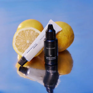 Brow Code Professional Brow Lightening System with 6% cream oxidant and lightening cream, displayed on a reflective surface with lemons