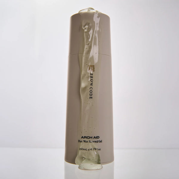 Brow Code Arch Aid Post Wax Renewal Gel with clear gel oozing down the sleek beige 200mL bottle, highlighting its soothing texture
