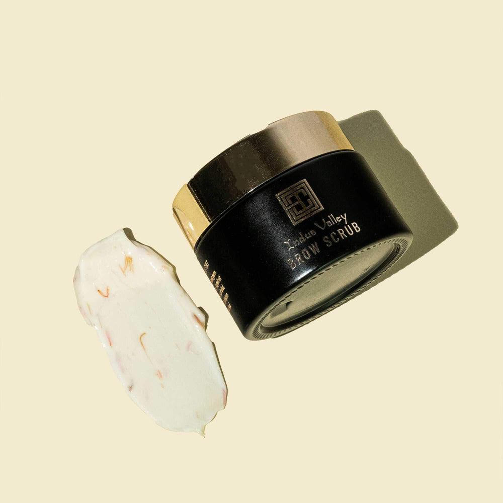 Brow Code Brow Scrub in an open black and gold jar with whipped formula visible