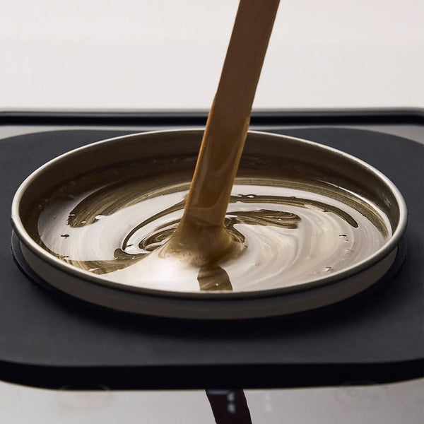 Brow Code Butter Bond Advanced Strip Wax being poured smoothly into a metal wax heater tin, showing its golden, creamy consistency