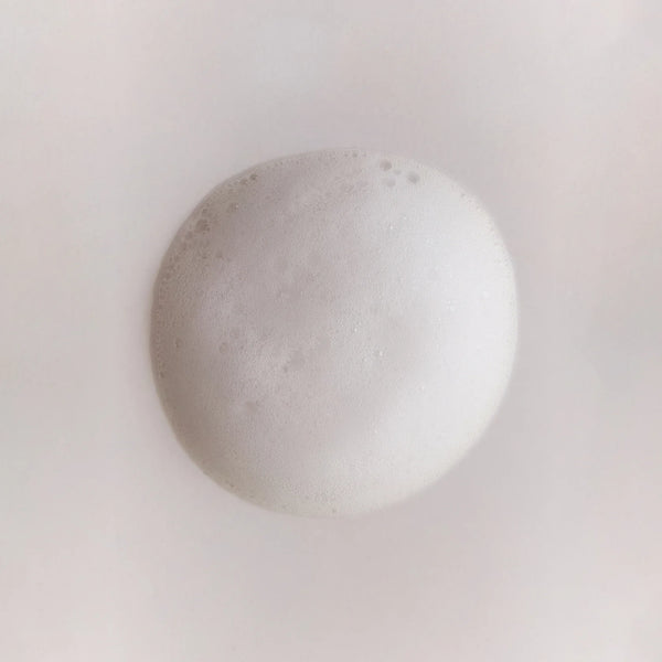 Close-up of a foamy white bubble from Brow Code First Base Ceramide Foaming Cleanser, showcasing its airy, gentle texture on skin