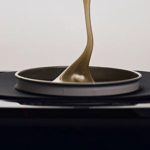 Brow Code silicone wax collar securely fitted on a wax heater, protecting the rim while golden wax drips inside the pot