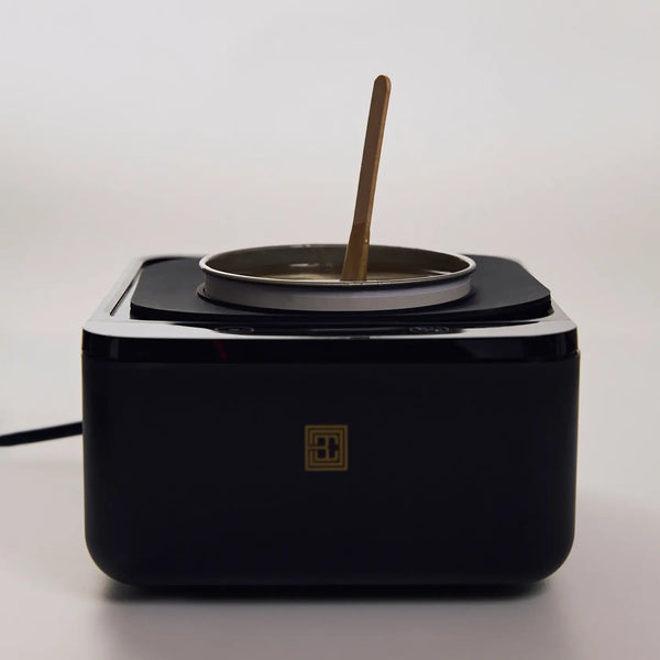 Brow Code silicone wax collar fitted on a black wax heater, holding a wax pot with melted wax and a wooden spatula