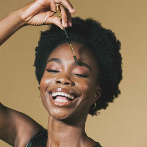 Model using Brow Code 122 Define & Line Brush – A radiant woman joyfully using the Brow Code 122 brush, showcasing its spoolie side for effortless brow grooming