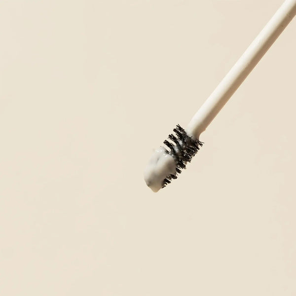 Close-up of the Brow Code Alias Brow Lamination Gel applicator with a precise spoolie brush coated in the product, highlighting its creamy texture