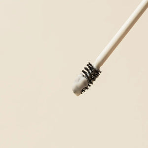 Close-up of the Brow Code Alias Brow Lamination Gel applicator with a precise spoolie brush coated in the product, highlighting its creamy texture