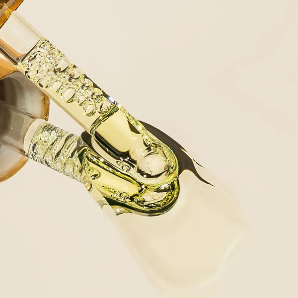 Close-up of Brow Code Brow Growth Oil dropper dispensing golden nourishing serum for eyebrow conditioning and enhancement