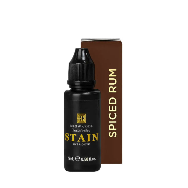 Brow Code Stain Hybrid Dye in Spiced Rum shade, featuring a 15ml matte black bottle and warm brown box designed for professional eyebrow tinting