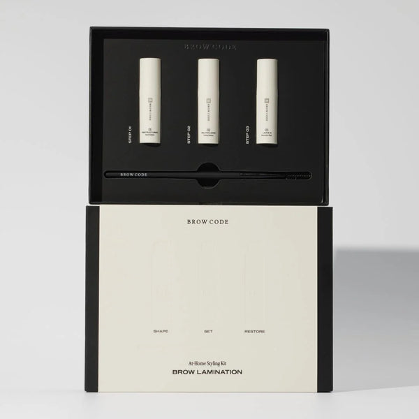 Brow Code At-Home Brow Lamination Kit with three cream tubes labeled Step 01 to Step 03 and a black applicator brush in a sleek box for shaping, setting, and restoring brows.