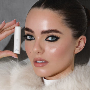 Model with sleek laminated brows holding Brow Code Step 02 Neutralizing Setting Solution, showcasing professional brow styling results.