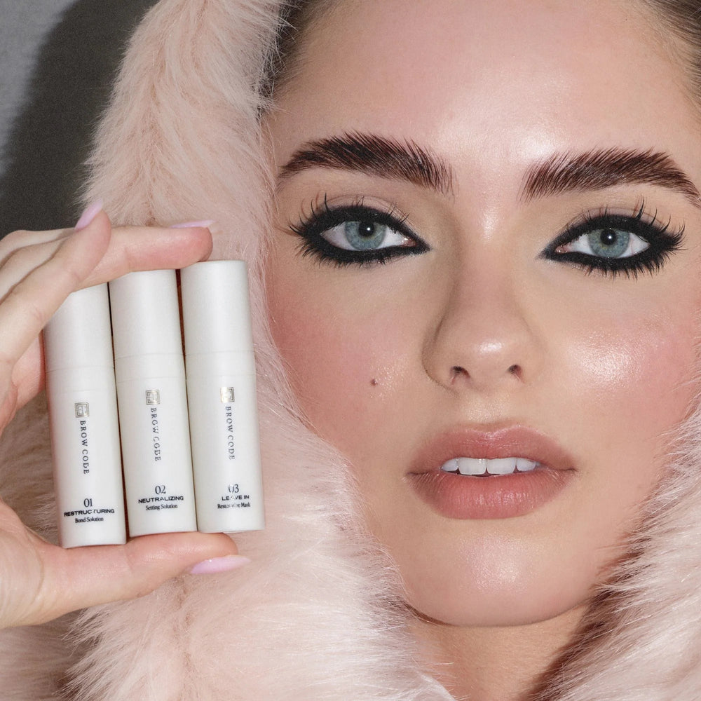 Brow Code At-Home Brow Lamination Kit with three cream tubes labeled Step 01 to Step 03 and a black applicator brush in a sleek box for shaping, setting, and restoring brows.