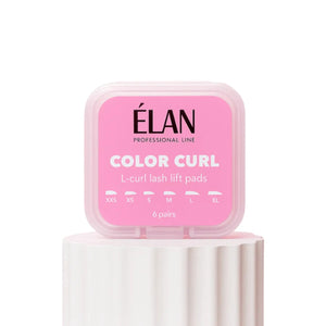 Élan Color Curl L-Curl Lash Lift Pads in stylish pink box placed on a white pedestal, containing six pairs of silicone shields in multiple sizes for creating defined L-curl lash lift results