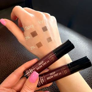 Hand showing swatches of ÉLAN Deep Brow Tint 2.0 in Spicy and Icy shades using 2% and 3% oxidant, alongside two product tubes.